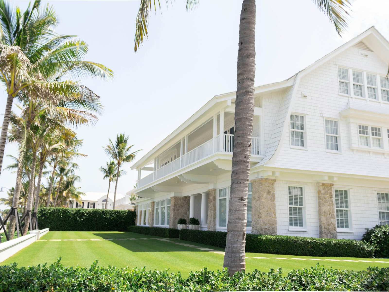 A white wooden Florida home framed by tall palm trees
